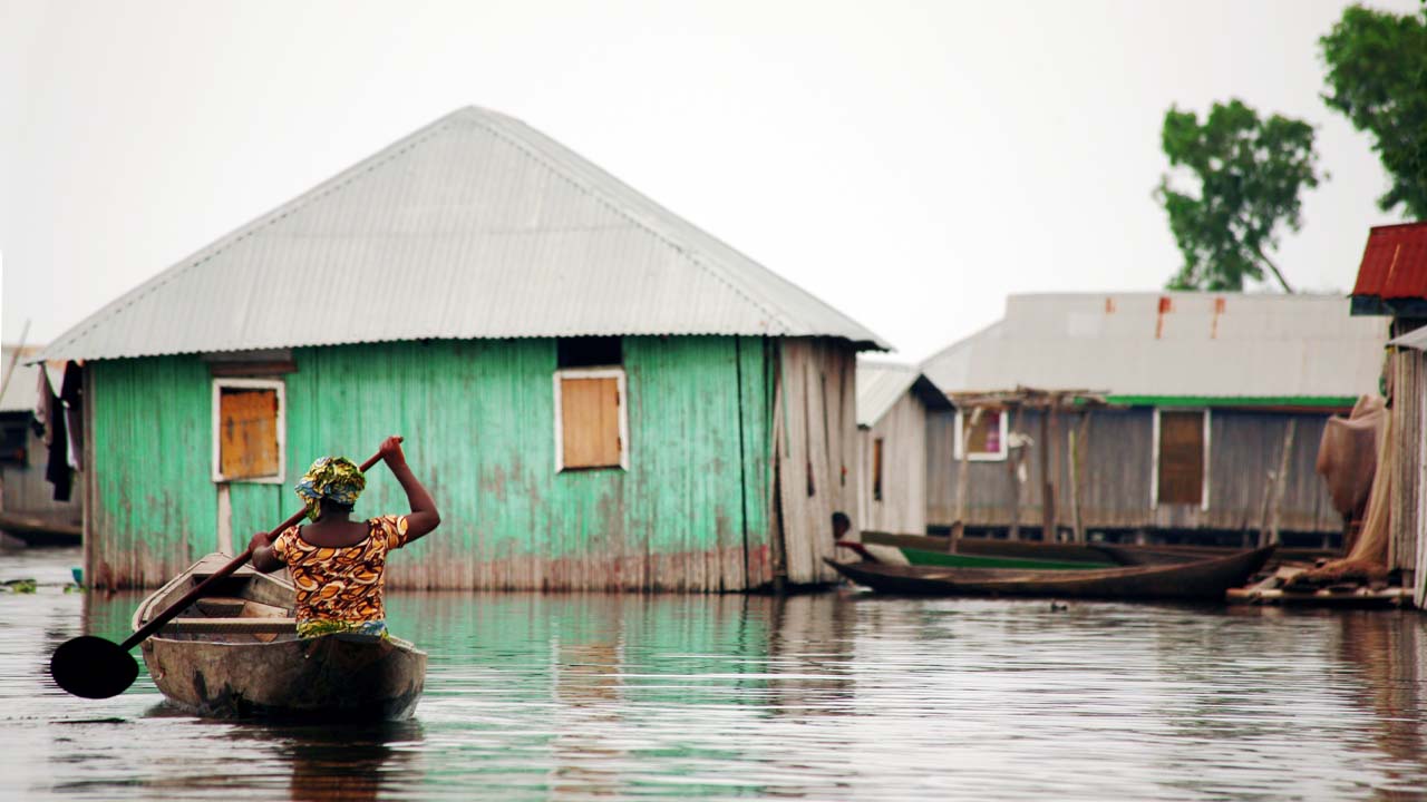 Woman in canoe in a flooded vilage